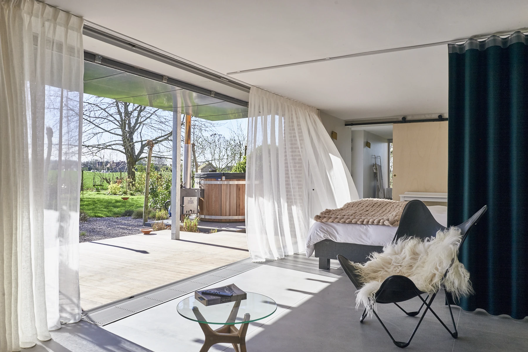La Suite Nordique ouverte sur la terrasse, le bain nordique et le jardin en été